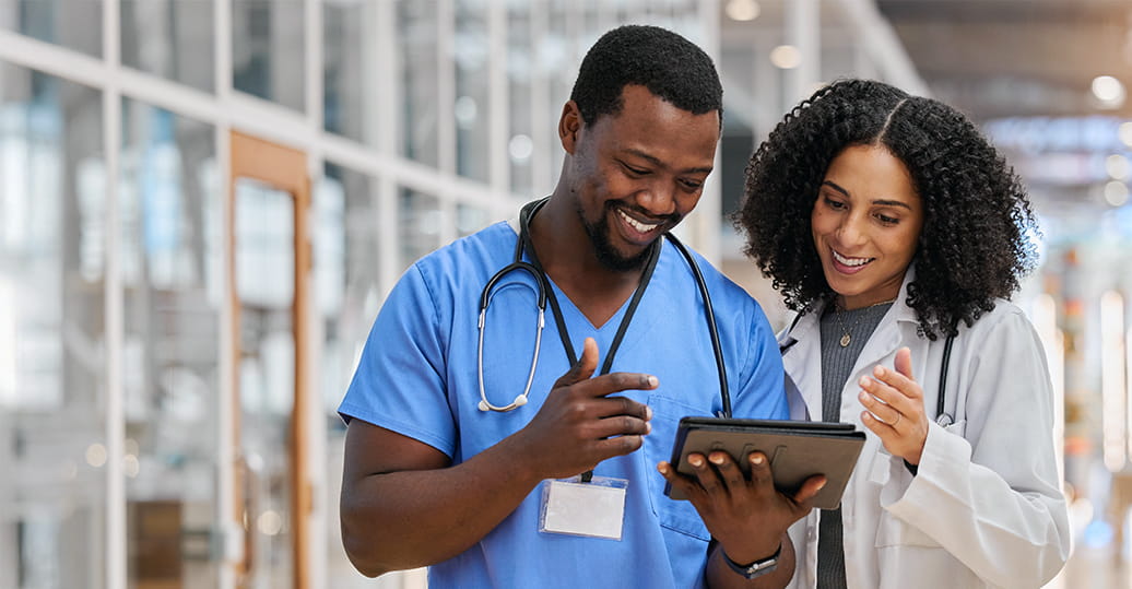 C3143 Best Employee Benefits for Healthcare Workers in Texas Two smiling healthcare professionals looking at and discussing something on a tablet computer
