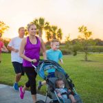 The image shows a family of five walking or running with a child in a stroller