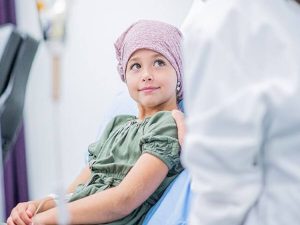 A young child wearing a head covering and resting, illustrating pediatric cancer care