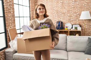 this image is about girl smiling and holding some boxes on hand

