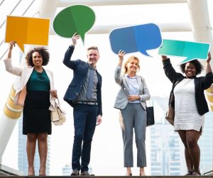 blog post communication Where to Find Critical Illness and Cancer Insurance for Your Business Four business professionals, holding up large, colourful speech bubble cutouts